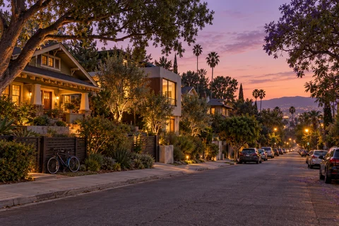 A neighborhood street with porch lights at dusk