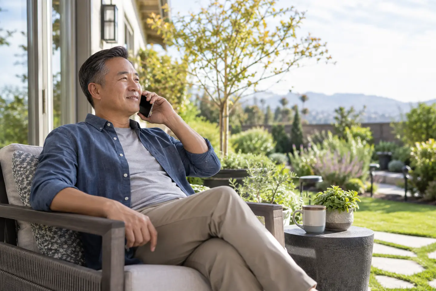 A homeowner speaking by phone on a sunny patio