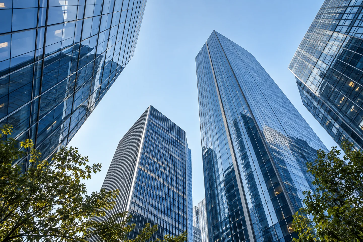 Glass office towers viewed from below against a blue sky.